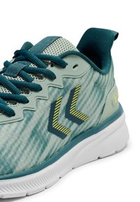 Jasnoniebieski but sportowy z teksturowaną cholewką, akcentami w kolorze morskim oraz geometrycznymi elementami wzornictwa. Posiada białą gumową podeszwę i zapięcie na sznurowadła.