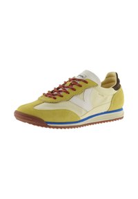 Sneaker low-profile in suede giallo, tessuto crema, tallone imbottito marrone, lacci rossi, logo bianco e striscia blu sulla suola in gomma.