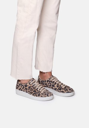 Leopardmønstrede sneakers med beige ruskindsoverdel, sorte detaljer, flade snørebånd og hvid gummisål, parret med off-white, cropped bukser.