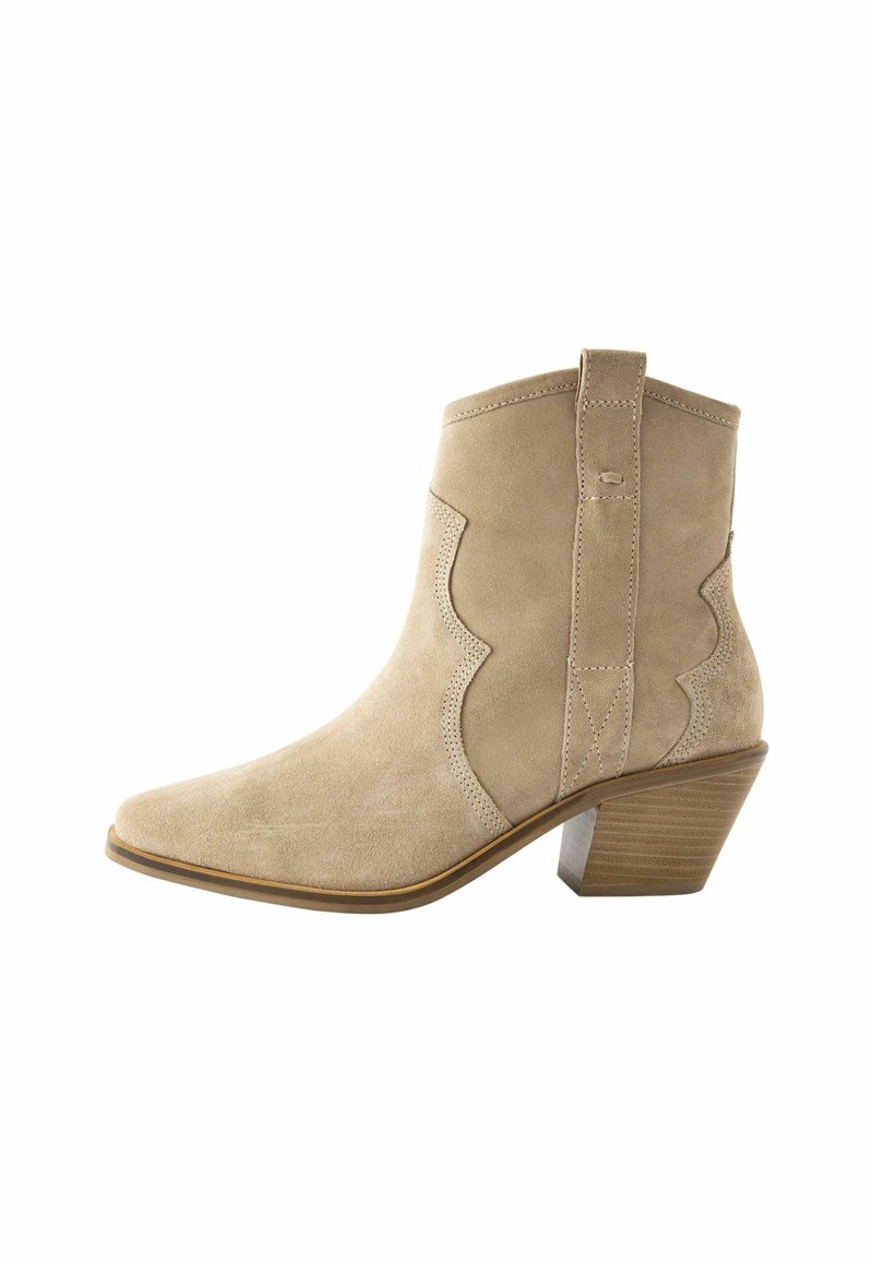 Beige mockasin stövlett med spetsig tå och böjda sömmar. Har en staplad klack och en dragflik bak för enkel påtagning.