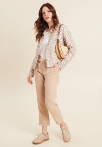 Leopardenmuster-Jacke, beige Leinenhosen und helle Sneaker. Umhängetasche mit gewebten Texturen und braunen Akzenten. Lässiges Outfit.