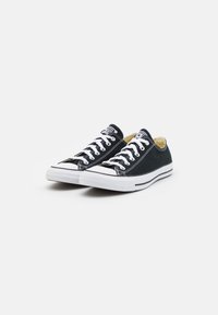 Schwarze Canvas-Sneaker mit weißen Gummisohlen, weißen Schnürsenkeln und schwarzem Steppstich. Klassisches Low-Top-Design mit runder Zehenkappe.