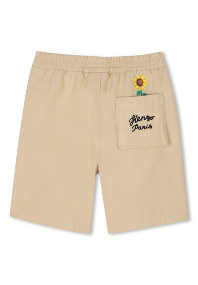 Shorts beiges avec une taille élastique, comprenant une poche avec une broderie "Kenzo Paris" et un design de tournesol. Texture de tissu lisse.