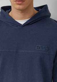 Felpa con cappuccio blu navy con coulisse, toppa frontale con la scritta "S.O. Elevated Casual Est. 1969" e cuciture a contrasto.