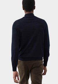 Granatowy sweter z wysokim kołnierzem, długimi rękawami i dopasowanym fasonem w talii. Gładka struktura dzianiny bez widocznych wzorów.