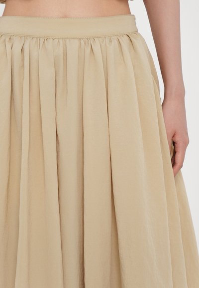 Beige, knielanger Rock mit einem gerafften elastischen Bund, aus leichtem Stoff. Hat eine glatte Textur und ein fließendes Design.