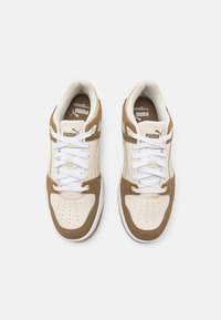 Braune und cremefarbene Sneaker mit weißen Schnürsenkeln, glattem Leder und Wildlederoberflächen, perforierter Zehenbox und Logo auf der Zunge und den Seitenpanelen.