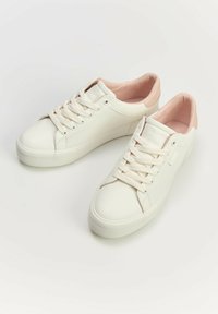 Białe syntetyczne sneakersy o gładkiej fakturze, z różowym materiałowym wykończeniem, płaskim sznurówkami i gumową podeszwą. Prosty, niskoprofilowy design.