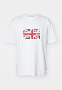 Camiseta de algodón blanca con un diseño desgastado de la Union Jack en rojo y azul en el centro. Con mangas cortas y estilo de cuello redondo.
