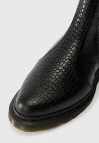 Μαύρη δερμάτινη μπότα μέχρι τον αστράγαλο με υφή που μοιάζει με δέρμα ερπετού. Διαθέτει στρογγυλή μύτη και ανθεκτική, στιβαρή καουτσούκ σόλα.