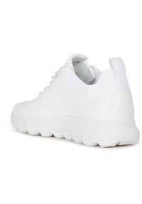 Vit sneaker med stickad ovandel, texturerad detaljering, en rem vid hälen och en tjock, vågmönstrad sula för dämpning.