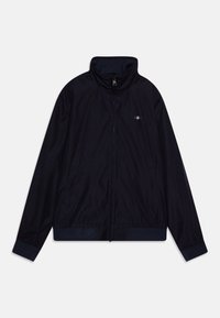 Giacca zip-up blu navy con colletto alto, dotata di due tasche laterali e polsini a coste. Il materiale sembra liscio e leggero. Piccolo emblema sul petto.