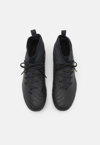 Black athletic shoes with a textured surface, circular patterns, shoelaces, and pull tabs; mid-top design and synthetic material.