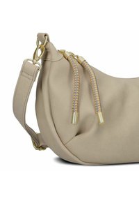 Borsa in pelle beige con una forma curva. Presenta accessori in oro e cordini intrecciati grigi e beige.