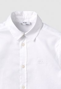 Vit bomullskjorta med krage, prydd med subtil brodering av BOSS-logotypen och standard knappstängningar. Slät textur.