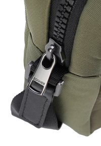 Borsa in tessuto verde oliva con una cerniera nera prominente, caratterizzata da un tirante in metallo argentato inciso con "BOGNER" e una superficie testurizzata.