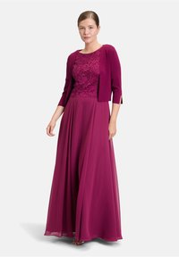 Robe bordeaux sombre avec un corsage en dentelle, jupe évasée et cardigan à manches trois-quarts. Tissu lisse et design superposé.