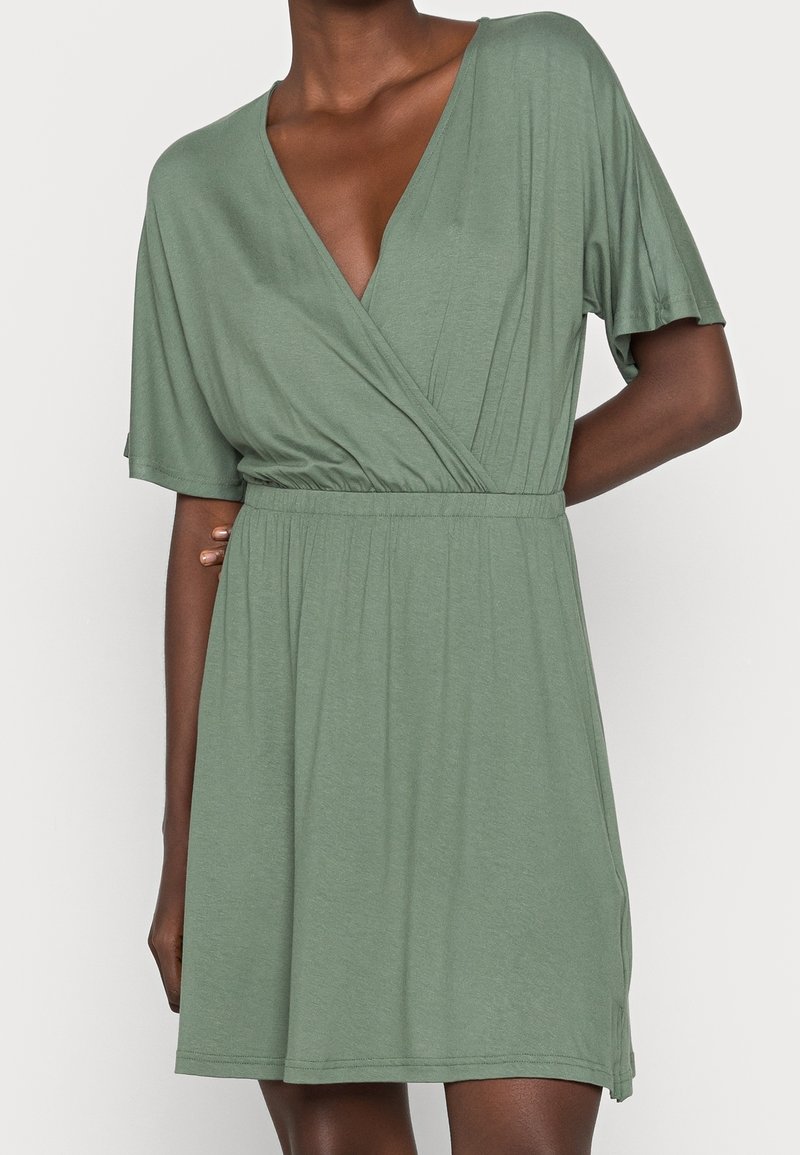 Robe verte à manches courtes avec un décolleté en V profond et une ceinture élastique, confectionnée dans un tissu doux et léger avec une coupe décontractée.