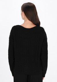 Zwarte kabelgebreide trui met een brede halslijn, losse pasvorm en gestructureerde stof, met lange mouwen en een geribbelde zoom.