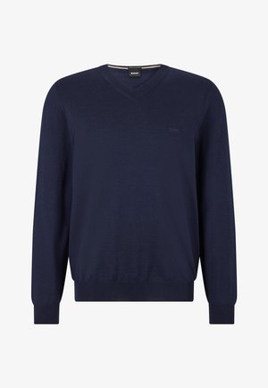 Marineblå v-hals genser laget av fint strikket materiale, med lange ermer, ribbestrikkede mansjetter og nedkant, samt subtil logo på brystet.