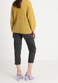 Keltainen paksu neule, mustavalkoraidalliset lyhyet housut ja vaaleanvioletit korkolapuiset kengät. Pehmeä materiaali ja väljä istuvuus.