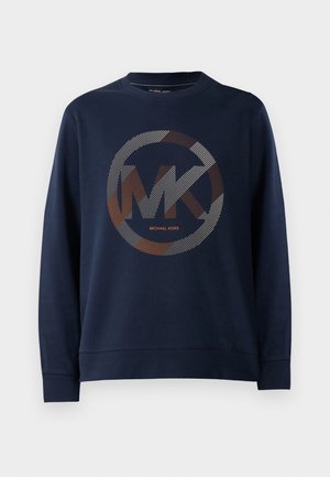 Tumesinine dressipluus, millel on suur ümmargune logo ning keskel "MK". Kujunduses on hõbedase ja oranži tooni triibumustrid.