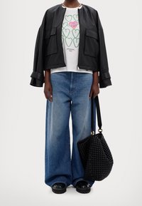 Musta nahkainen pommi takki, valkoinen t-paita vihreällä sydänprintillä, leveälahkeiset siniset farkut ja kudottu musta laukku. Mustat korokepohjaiset kengät.