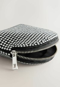 Čierny zipsový vrecúško pokryté striebornými rhinestones, s textúrovaným povrchom a odolným zipsom pozdĺž okraja.