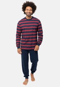 Camicia a maniche lunghe a righe rossa e blu navy, abbinata a pantaloni da pigiama blu navy a tinta unita. Tessuto morbido in cotone con polsini e vita a coste.