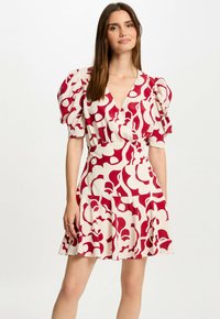 Rode en crèmekleurige jurk met bloemenprint, met pofmouwen, diepe V-hals, aansluitende taille en uitlopende rok, gemaakt van lichte stof met een zachte textuur.