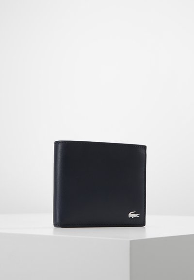 Portefeuille en cuir bleu marine avec une texture lisse, design bi-fold et un petit logo en argent sur le devant. Style simple et moderne.
