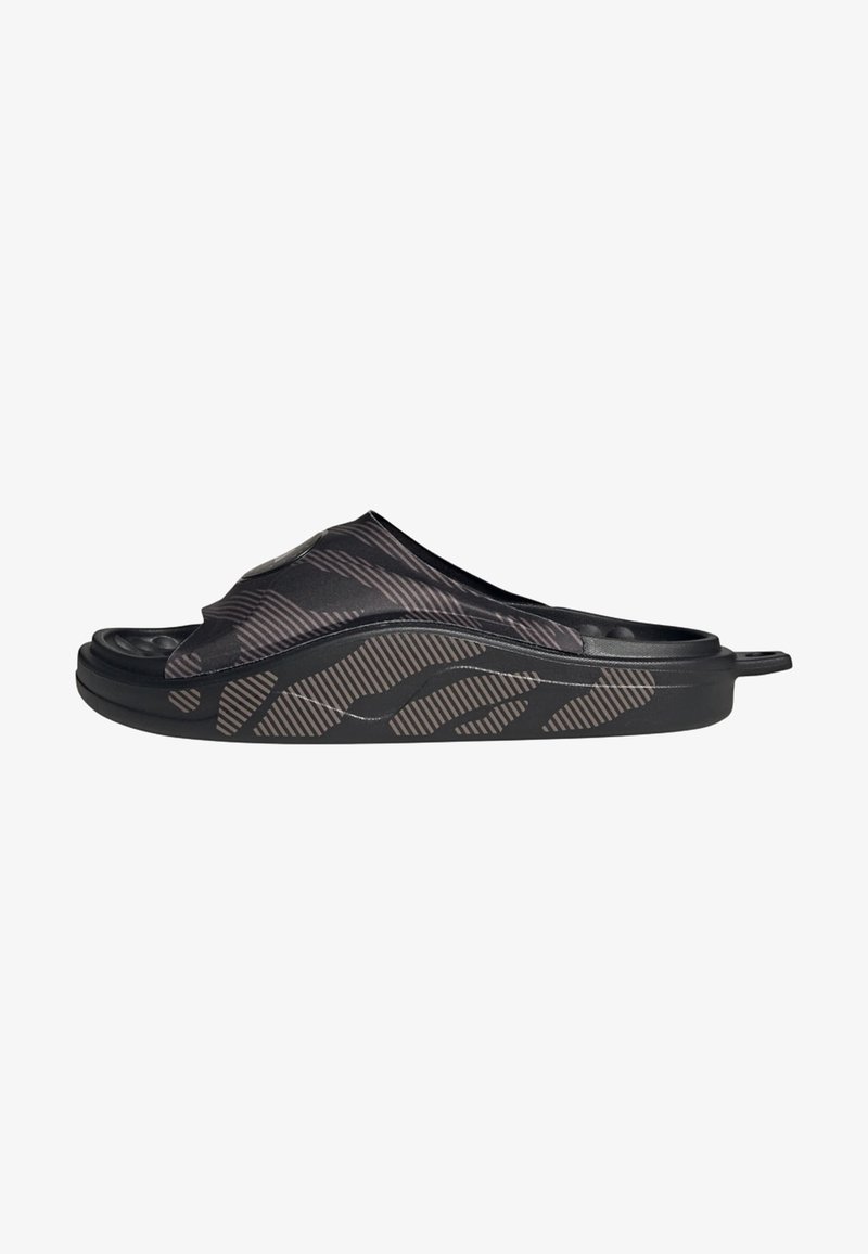 Sandalia de slide negra con un upper texturizado y con patrón, y una suela gruesa. Presenta un acabado suave y una ligera curva en el diseño.