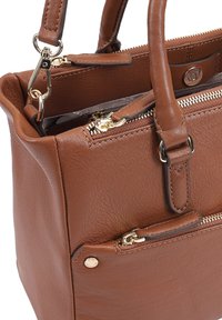 Sac à main en cuir marron avec quincaillerie dorée, poignées supérieures et poche zippée extérieure. Surface texturée et design structuré.