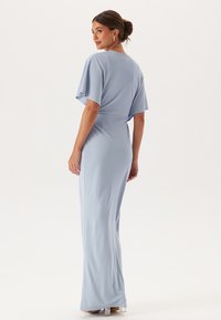 Jasnoniebieska sukienka wykonana z gładkiego materiału, o dopasowanej sylwetce, krótkich falbaniastych rękawach i długości do podłogi.