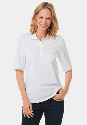 Witte poloshirt met korte mouwen, knoopsluiting en geborduurd logo. Zacht katoenmateriaal met een relaxte pasvorm, gecombineerd met donkere spijkerbroek.