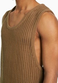 Brown knitted tank top featuring a loose, open weave, wide armholes, and a rounded neckline, showcasing a textured fabric.
