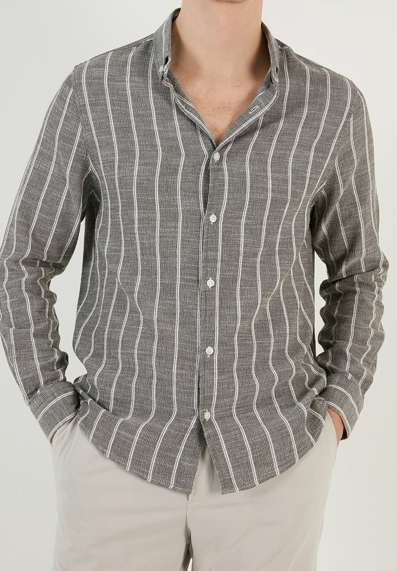 Grijze button-up shirt met witte verticale strepen, gemaakt van textuurstof. Beschikt over een kraag, lange mouwen en een standaard knoopsluiting.