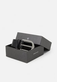 Zwarte leren riem met een zilveren rechthoekige gesp, gepresenteerd in een open zwarte doos met een logo. Gladde textuur, minimalistisch ontwerp.