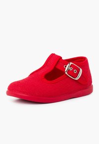 Zapato de tela roja con superficie texturada, punta redondeada, diseño de tira en T y detalle de hebilla plateada. Suela de goma plana para mayor comodidad.