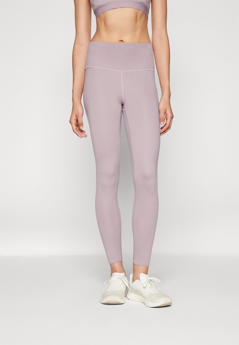 Lys lilla leggings med høyt liv, glatt tekstur og minimalt med sømdetaljer, kombinert med hvite sportssko.