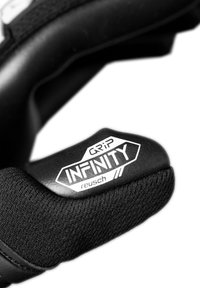 Close-up of a black Reusch Infinity Grip goalkeeper glove showing padded fingers and textured wrist area.