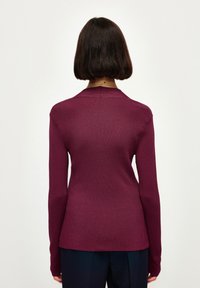 Pull à manches longues bordeaux côtelé avec une coupe légèrement ajustée et un col rond, vu de dos, révélant une texture lisse.