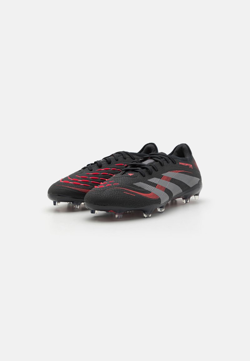 Melnas un sarkanas futbola botas ar teksturētu virsmu, kuras rotā dinamiskas līnijas un pelēks akcenta tonis. Kliba zoles nodrošina saķeri uz zāles virsmām.