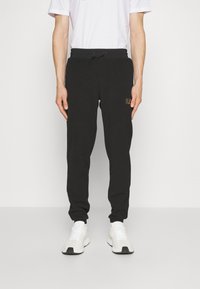 Svarta joggingsbyxor i ett strukturerat tyg, med elastisk midja och dragsko. Liten detalj med guldlogotyp på framsidan.