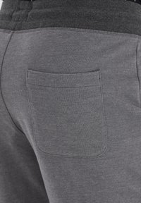Joggers de algodón gris con una mezcla de tejidos, que presentan una cinturilla acanalada, un bolsillo trasero y una textura suave. En general, un diseño casual.