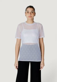 Camiseta blanca translúcida con cuello redondo y mangas cortas, que presenta patrones sutiles y un diseño en capas sobre una base sólida.