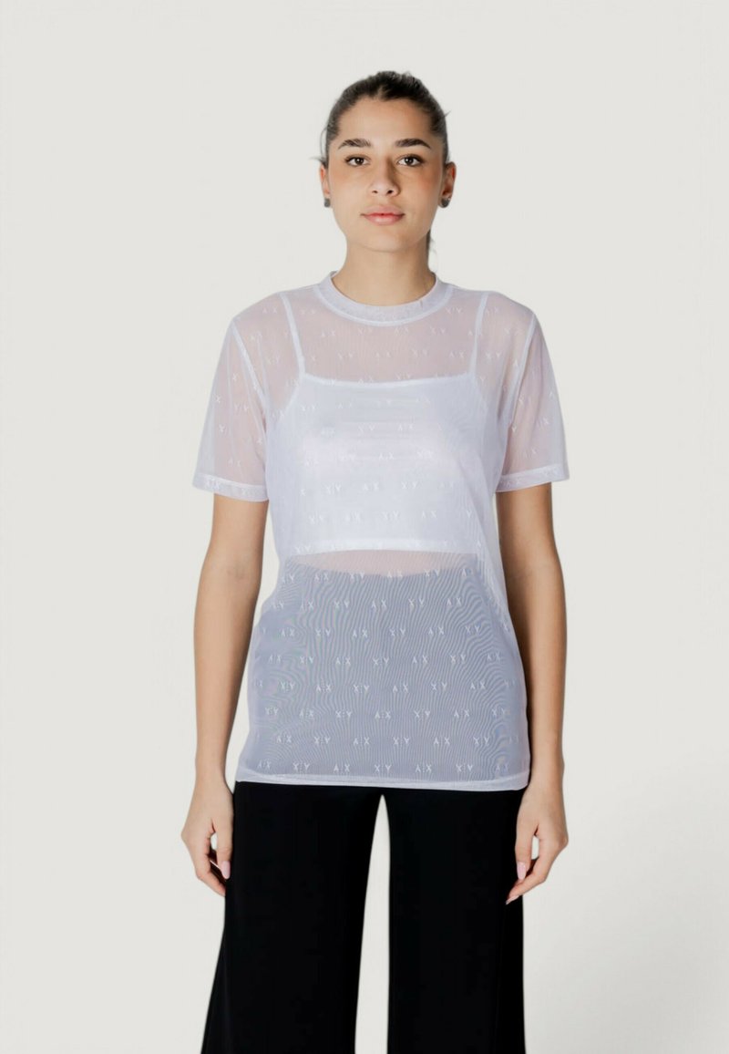 Camiseta blanca translúcida con cuello redondo y mangas cortas, que presenta patrones sutiles y un diseño en capas sobre una base sólida.