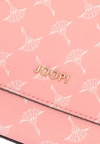 Tessuto rosa chiaro con motivi bianchi. Logo "JOOP!" in metallo dorato, ben visibile. Superficie strutturata che aggiunge interesse visivo.