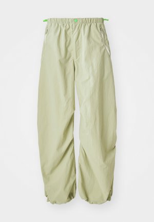 Pantaloni oversize verde chiaro con vita elasticizzata. Presentano tasche con zip e dettagli con cordino in vita per una vestibilità regolabile.