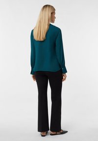 Teal long-sleeve shirt with a smooth texture and slight shine, paired with black fitted trousers and flat black shoes.
